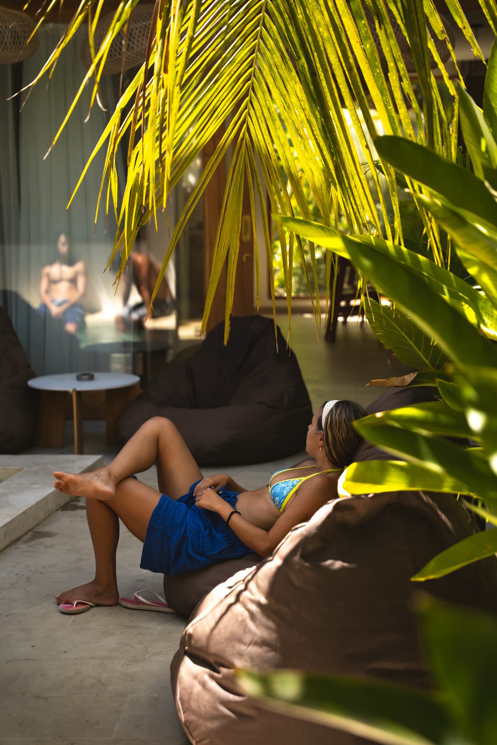 Zona de estar exterior de la villa, con puf y vegetación tropical junto a la piscina